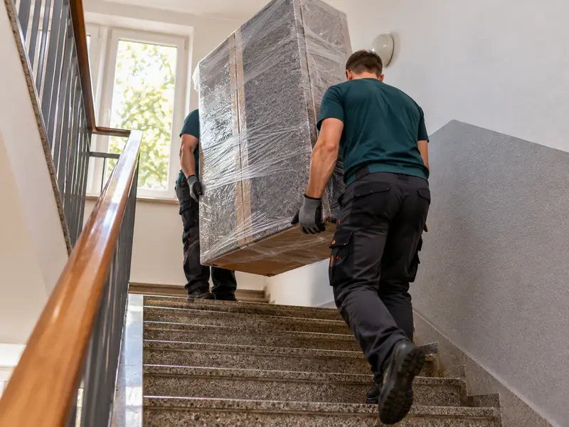 Privatumzug Leverkusen: Umzugshelfer tragen einen Schrank im Treppenhaus